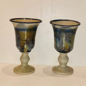 May include: Two ceramic goblets with a blue and brown glaze. The goblets have a flared top and a round base.