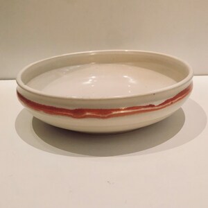 May include: A white ceramic bowl with a wide rim and a single band of reddish-brown glaze around the top.
