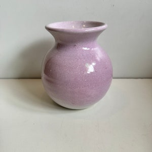 Puede incluir: Un jarrón pequeño, redondo, de cerámica de color púrpura claro con una superficie texturizada.