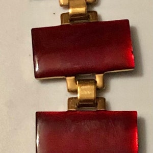 Peut inclure: Un bracelet rouge et or avec des pierres rouges rectangulaires et des maillons dor&eacute;s.