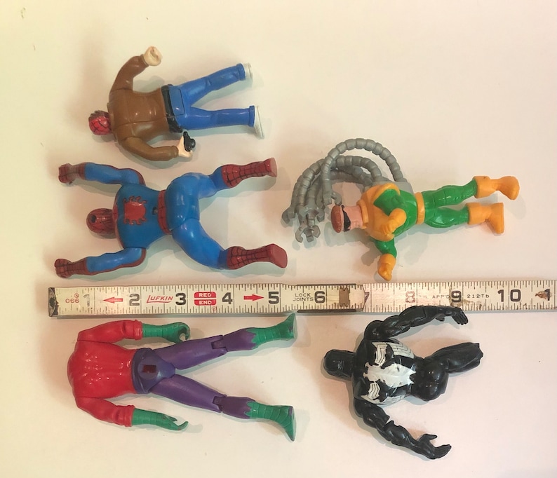 May include: Five action figures of superheroes, including Spider-Man, Venom, and Doc Ock. The figures are made of plastic and are painted in various colors, including red, blue, green, black, and yellow. The figures are posed in action poses and are ready for battle.