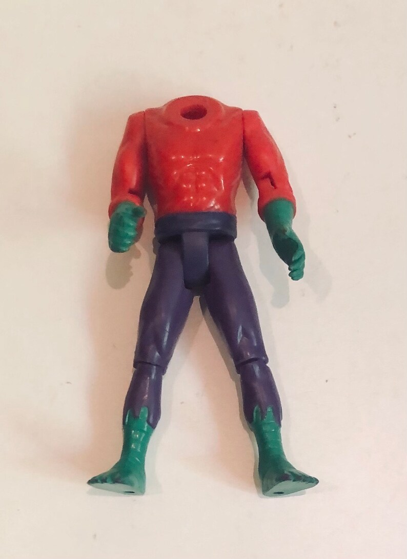 May include: A headless action figure with a red torso, purple pants, and green feet.