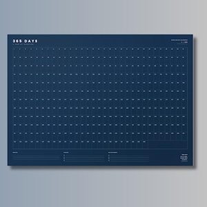 Puede incluir: Un calendario de pared azul oscuro de 365 días con una cuadrícula de cuadrados numerados del 1 al 365. La esquina superior izquierda muestra el texto 365 DAYS A YEAR OF INTENTION. La parte inferior incluye tres áreas con líneas etiquetadas como NOTES, FOCUS y MILESTONES.