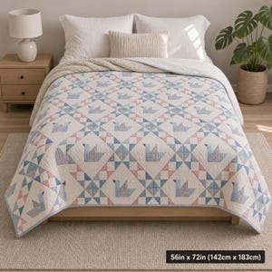 Puede incluir: Una colcha con un patrón geométrico repetitivo de aves estilizadas en tonos azules y rosas sobre un fondo blanco. La colcha mide 142 cm por 183 cm y está extendida sobre una cama con almohadas blancas y un cojín lumbar de color crema.