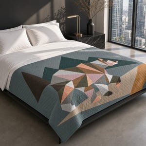 May include: A quilt featuring a geometric, low-poly style bear graphic in shades of brown, pink, and white against a dark teal background with mountain shapes. The bedspread has a quilted texture and covers a bed with white pillows and sheets.
