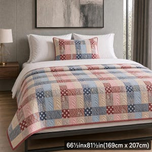 Könnte beinhalten: Eine Steppdecke und ein passender Kissenbezug mit einem gewebten Patchwork-Muster in Blau-, Rosa- und Cremetönen mit Punkten und Blumenmotiven. Das Set misst 169 cm mal 207 cm und ist auf einem Bett mit weißen Kissen ausgebreitet.