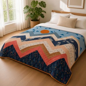 Puede incluir: Una colcha acolchada con un patrón de paisaje montañoso con capas de rayas en zigzag azul marino, coral y crema. El diseño incluye pequeños árboles impresos, siluetas de ciervos, un sol naranja sólido y un borde de color naranja oscuro.