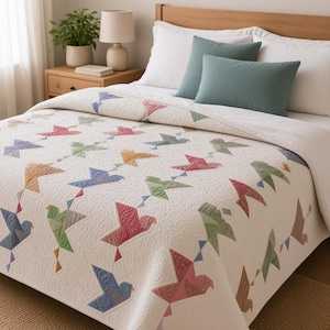 May include: A white quilt featuring a repeating pattern of multi-colored birds in shades of pink, blue, green, and yellow. The quilt has a textured, quilted surface and is draped over a bed with white pillows and a solid teal accent pillow.