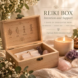 May include: A light-colored wooden box with a hinged lid featuring four engraved Reiki symbols and the text CKR, SHK, HSZSN, DKM. The box contains small paper slips, a sprig of lavender, and a rose quartz stone, next to a lit candle.