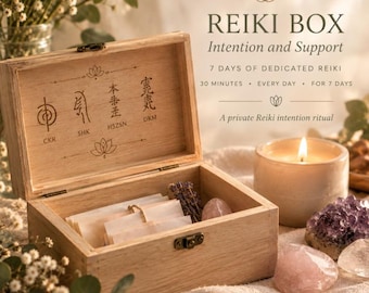Puede incluir: Una caja de madera clara con tapa abatible que presenta cuatro símbolos Reiki grabados y el texto CKR, SHK, HSZSN, DKM. La caja contiene pequeños papeles, una ramita de lavanda y una piedra de cuarzo rosa, junto a una vela encendida.