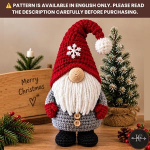 May include: A crocheted gnome featuring a tall red hat with a white snowflake and pom-pom, a beige nose, a long white beard, a gray body with two wooden buttons, and black feet. The text reads: PATTERN IS AVAILABLE IN ENGLISH ONLY.