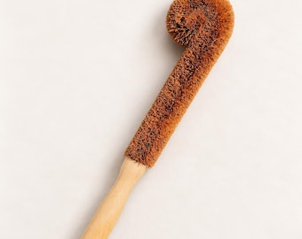 May include: A long-handled cleaning brush featuring a light-colored wooden handle with a small hole at the base and a thick, brown, stiff-bristled head that curves into a rounded, spiral-like shape at the top for scrubbing.