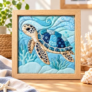 May include: A square framed fabric wall art piece featuring a quilted sea turtle swimming through blue waves. The turtle has a tan head and flippers with dark spots, and a shell composed of various blue patterned fabric patches. Light blue coral sits below.