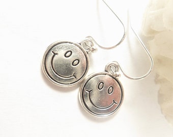 May include: Silver smiley face earrings with a simple hook design. The earrings are small and delicate.