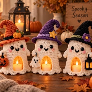 May include: Three crocheted ghost figurines, each wearing a pointed hat in orange, purple, or black. The ghosts are off-white with black eyes and pink cheeks, featuring a hollow centre containing a small lit candle and holding miniature accessories.
