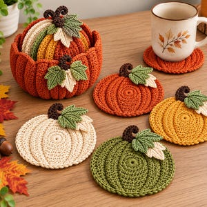 Könnte beinhalten: Ein Set aus gehäkelten, kürbisförmigen Untersetzern in Orange, Gelb, Creme und Grün, jeweils mit einem dunkelbraunen Stiel und zwei kleinen Blättern. Die Untersetzer werden in einem passenden, gehäkelten, kürbisförmigen Korb aufbewahrt.