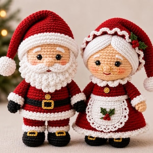 Op de afbeelding: Twee gehaakte poppen die de Kerstman en Mevrouw Kerst voorstellen. De Kerstman draagt een rood pak met witte randen, een zwarte riem en een gouden gesp. Mevrouw Kerst draagt een rode jurk met een wit schort met hulstbessen en een witte muts.