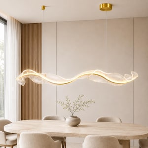 Könnte beinhalten: Eine lineare Pendelleuchte mit einem langen, wellenförmigen, halbtransparenten Glasschirm und einem integrierten goldfarbenen Metallrahmen. Die Leuchte ist mit zwei dünnen Kabeln an goldfarbenen, runden Deckenbefestigungen aufgehängt.