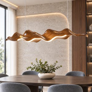 Op de afbeelding: Een lineaire hanglamp met een lang, golvend houten lichaam met een rijke bruine houtnerf. De lamp hangt aan dunne kabels en is voorzien van een doorlopende, helderwitte LED-lichtstrip langs de gebogen onderkant.