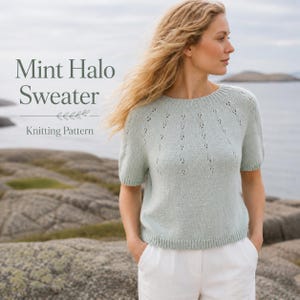 Peut inclure: Un pull vert menthe à manches courtes avec une encolure ronde et un motif de points ajourés sur l'empiècement. Le texte Mint Halo Sweater Knitting Pattern est affiché sur le côté gauche de l'image au-dessus d'un petit motif de feuille.