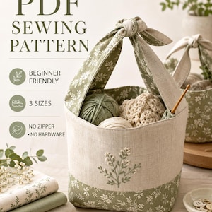 May include: A fabric storage basket with a sage green and white floral print, featuring a knotted handle and an embroidered botanical design on the front. The basket contains balls of yarn and a wooden crochet hook, with text reading PDF SEWING PATTERN.