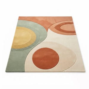 May include: A rectangular area rug featuring an abstract design with overlapping geometric shapes in shades of sage green, mustard yellow, terracotta, and cream. The surface displays varied textures with carved circular lines and smooth sections.
