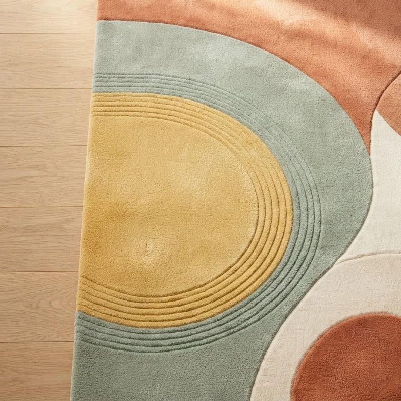 May include: A tufted area rug featuring a geometric pattern of concentric semicircles and curved shapes. The design incorporates a palette of muted terracotta, soft sage green, mustard yellow, and cream, with carved lines adding texture.