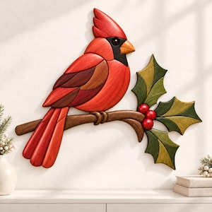 May include: A wall-mounted wooden art piece depicting a bright red cardinal bird perched on a brown branch. The bird features dark red and brown wing details with a black mask around its orange beak. Three green holly leaves and red berries.