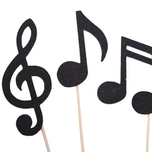 May include: Three black musical note cutouts on sticks. The notes are a treble clef, a quarter note, and an eighth note.