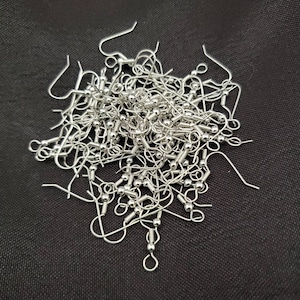 May include: A pile of silver earring hooks with a small ball at the end of each hook.