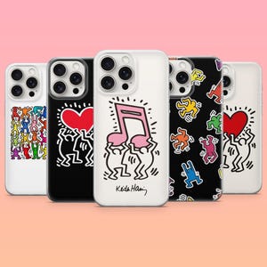May include: Five smartphone cases featuring Keith Haring artwork. Designs include colorful dancing figures, red hearts, and a pink musical note. The cases are displayed in a row against a light pink background, showcasing various artistic patterns.