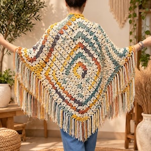 May include: A triangular crochet shawl featuring a multi-colored granny square pattern in shades of cream, mustard yellow, terracotta, and teal. The garment is finished with long, dangling fringe along the bottom edges, creating a textured look.