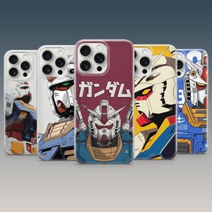 Könnte beinhalten: Fünf Smartphone-Hüllen mit verschiedenen grafischen Illustrationen eines weißen, blauen und gelben Roboters. Die mittlere Hülle zeigt den Roboterkopf mit dem japanischen Text ガンダム in Weiß darüber auf einem dunkelroten Hintergrund.