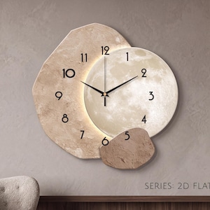 May include: A wall clock featuring a circular, illuminated moon-like face with black numerals one through five, partially overlapping a textured, beige, irregular-shaped backing with black numerals seven through eleven. The text SERIES: 2D FLAT is visible.