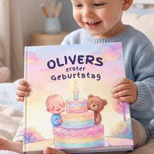 May include: A hardback book with a pastel-coloured illustration on the front cover featuring a baby and a teddy bear standing next to a three-tiered birthday cake with a single lit candle. The text on the cover reads OLIVERS erster GEBURTSTAG.