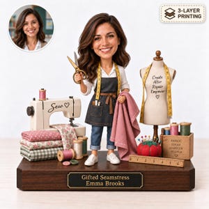 Puede incluir: Una figura cabezona personalizada de una mujer con cabello castaño, camisa blanca, delantal oscuro y jeans, sosteniendo tijeras. Incluye una máquina de coser, telas, un maniquí con texto, un alfiletero y una base de madera con una placa de nombre.