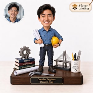 Puede incluir: Una figura cabezona personalizada de un ingeniero con camisa azul, pantalones oscuros y botas marrones, sosteniendo planos y un casco amarillo. La base incluye una placa con el nombre Creative Engineer Daniel Kim, libros, un modelo de puente, un portalápices con el texto Build Solve Improve Together y un calibre.