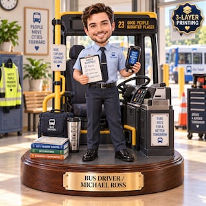 Könnte beinhalten: Eine individuelle Wackelkopf-Figur eines Busfahrers namens Michael Ross, stehend in einem Bus-Cockpit. Die Figur trägt ein hellblaues Hemd und eine dunkle Hose und hält einen Routenplan sowie ein Handgerät. Der Sockel hat ein Messingschild.