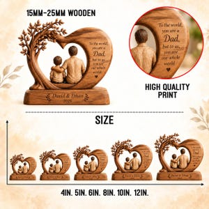 May include: A wooden heart-shaped sculpture featuring a tree and two figures, with the text 'To the world, you are a Dad, but to us, you are our whole world' and 'David & Ethan 2026'. The item is available in sizes from 4 inches to 12 inches.