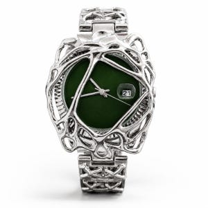 May include: A silver-toned wristwatch featuring a dark green circular dial with silver hands and a date window displaying the number 21. The watch case and bracelet are encased in an intricate, organic, web-like metal structure with cutouts.