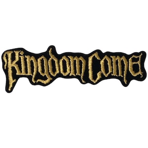 Op de afbeelding: Een geborduurde patch met de tekst Kingdom Come in een gestileerd, gotisch geïnspireerd goudkleurig lettertype. De letters zijn gestikt met metallic gouddraad op een effen zwarte stoffen achtergrond, wat zorgt voor een textuurrijk contrast.