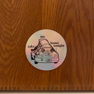 May include: A white sticker with a black outline of a car with a roof rack and the words "take me home tonight" around it.