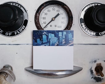 May include: A white medical device with a round gauge that reads up to 100. The gauge has a black needle and black markings. The device has a black knob labeled "Increase Pressure" and another black knob labeled "Ease of Flow". A white card with a blue and white image is attached to the device.
