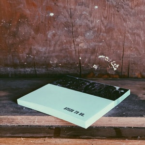 May include: A light blue notepad with the text "DIY TO DO." printed on the front. The notepad is sitting on a wooden surface.