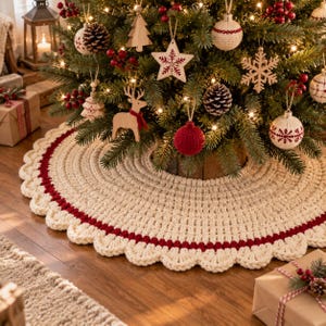 Puede incluir: Una falda de &aacute;rbol de Navidad redonda tejida a ganchillo en color crema, con una banda circular gruesa de color rojo oscuro y un borde festoneado. La falda est&aacute; hecha de lana gruesa y se coloca en la base de un &aacute;rbol decorado.
