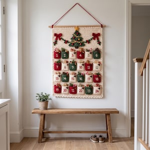 May include: A cream-colored crocheted wall hanging advent calendar featuring twenty-four numbered pockets in red, green, and white. The top displays a crocheted Christmas tree and red bows, suspended from a wooden rod with a red string.