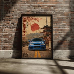 May include: A framed poster featuring a blue Nissan Skyline GT-R R34 parked on a road. The background displays a large red sun, Mount Fuji, a pagoda, and cherry blossoms. Japanese text is visible on the left, with the text NISSAN SKYLINE GT-R at the bottom.