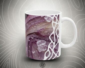 Puede incluir: Una taza de cerámica blanca con un estampado gráfico de cebollas rojas en rodajas con cristales de sal gruesa. El diseño incluye un patrón orgánico blanco similar a una red en el lado derecho. El texto ASSEMBLE WONDER está impreso en negro debajo.