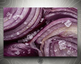 Puede incluir: Una vista de cerca de capas de cebolla morada en rodajas con cristales de sal marina gruesa esparcidos. La imagen muestra anillos concéntricos de color púrpura intenso y blanco translúcido, con el texto ASSEMBLE WONDER en la parte inferior.