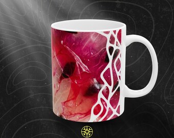 Puede incluir: Una taza de cerámica blanca con un diseño abstracto vibrante que presenta remolinos en tonos magenta intenso, carmesí y negro. Una superposición gráfica blanca similar a una red cubre el lado derecho. El texto ASSEMBLE WONDER aparece debajo.